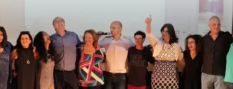 שורת בוגרים של מכללת קגן על במה, ידיים על הכתפיים